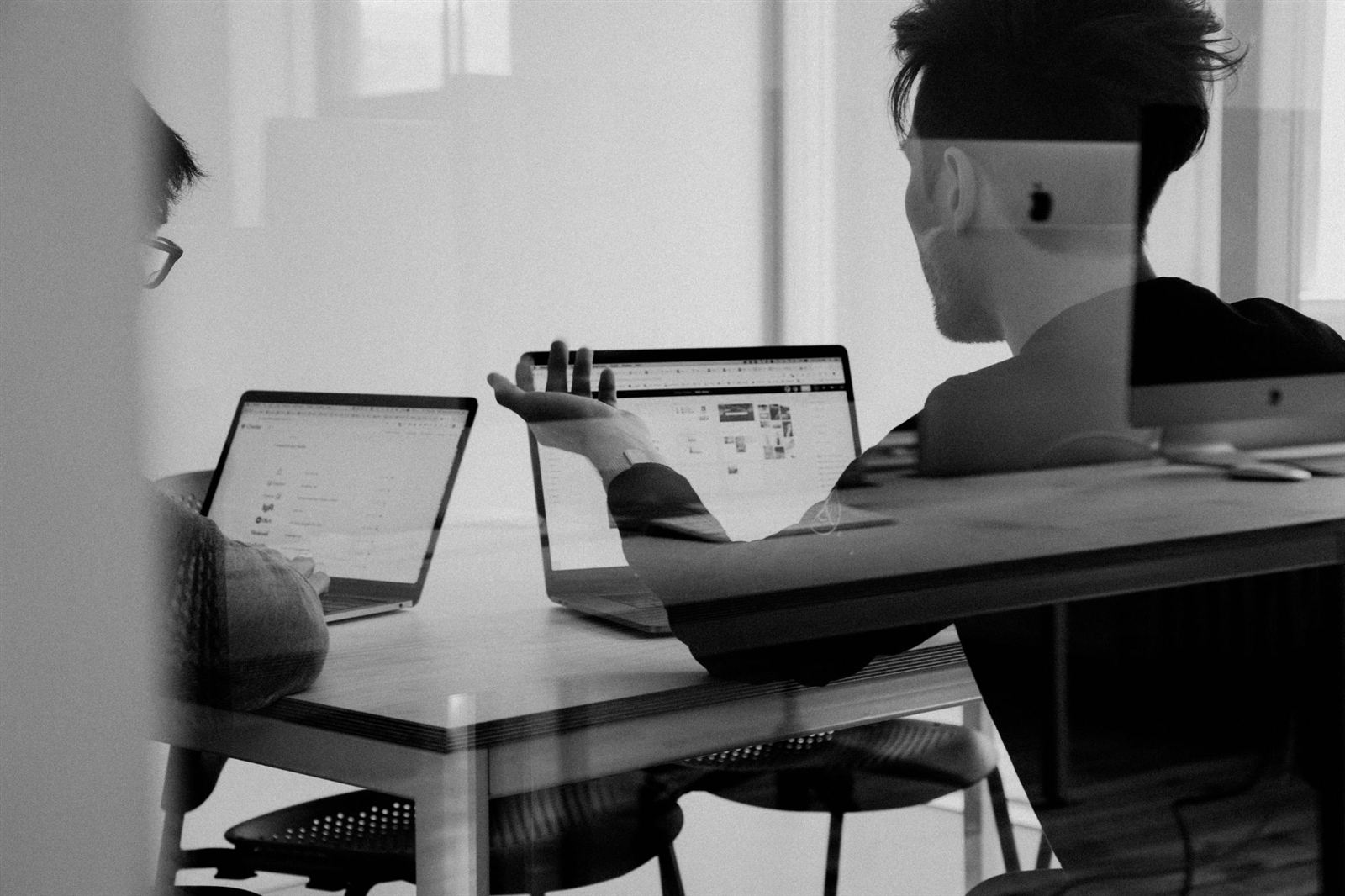 Two people talking a project through over their laptops