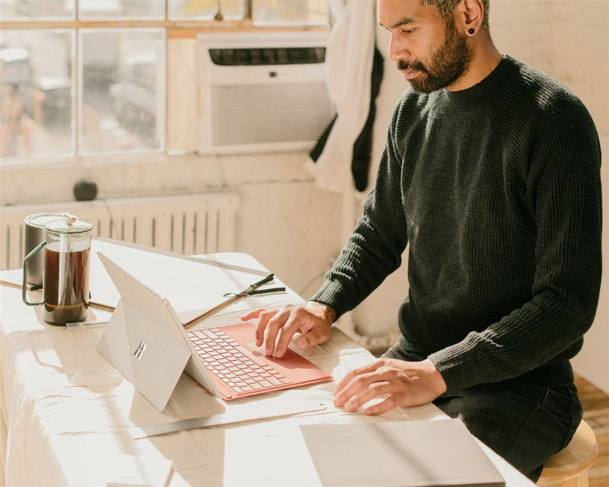 A business owner working on a laptop at a sunlit table