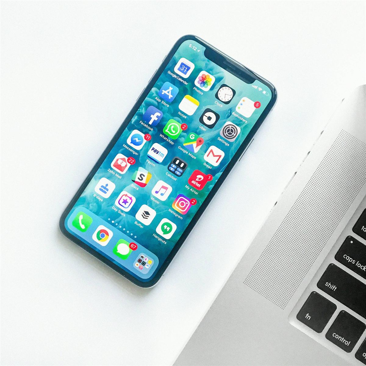 A smartphone showing a home screen full of apps, next to a laptop
