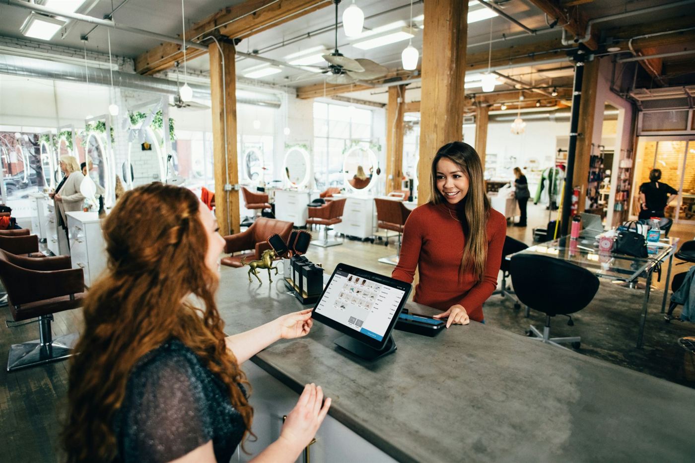 A salon customer paying at the front desk on a tablet till